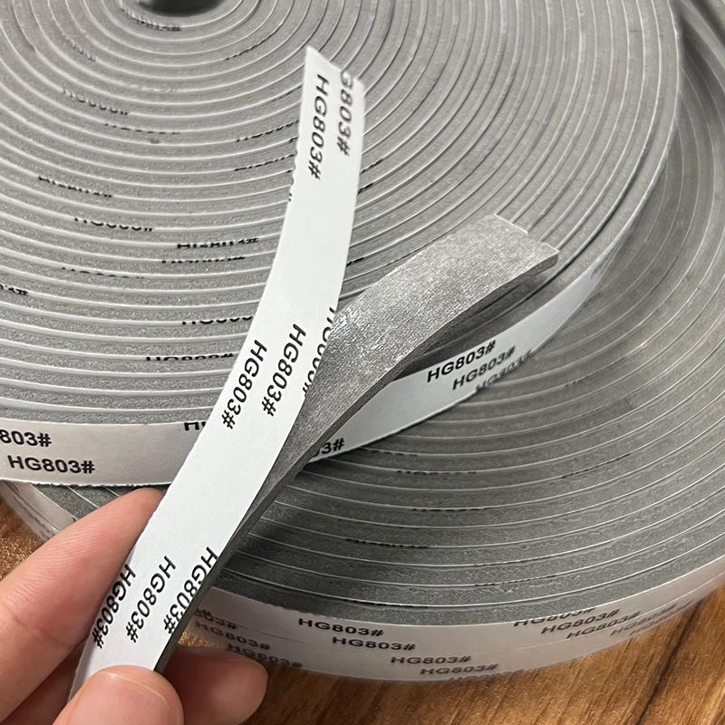 Hand held grey PE foam strip showing adhesive release liner surface