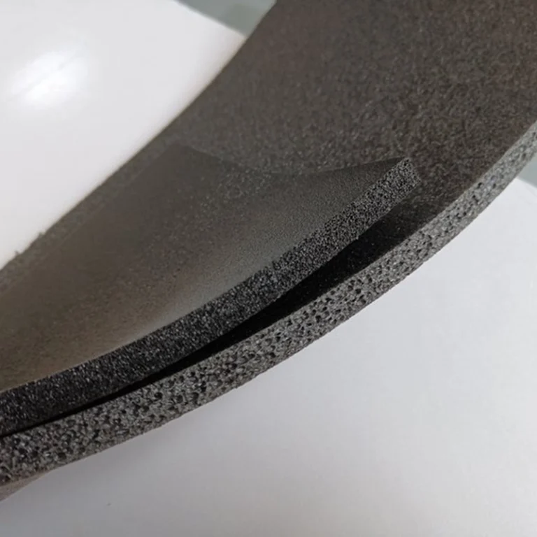 Bent black XPE foam sheet revealing layered composite interface